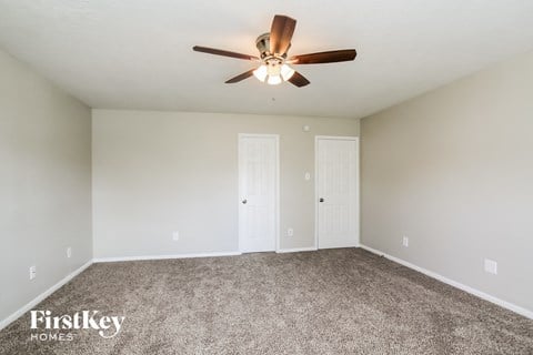 the spacious living room with ceiling fan and carpet