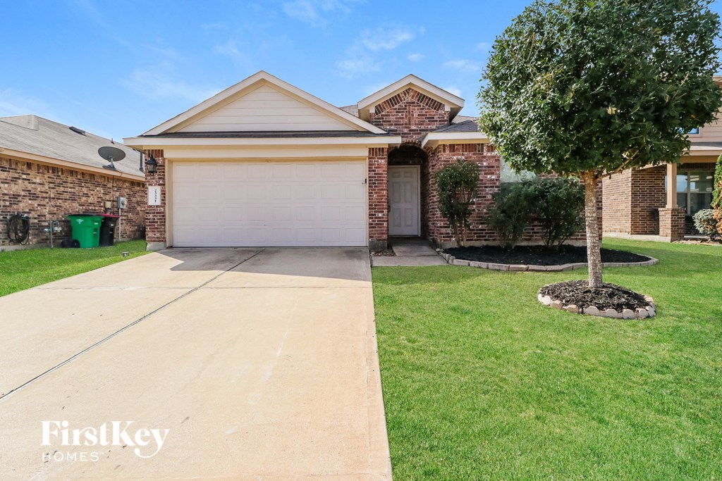 an empty driveway in front of a brick house with a tree