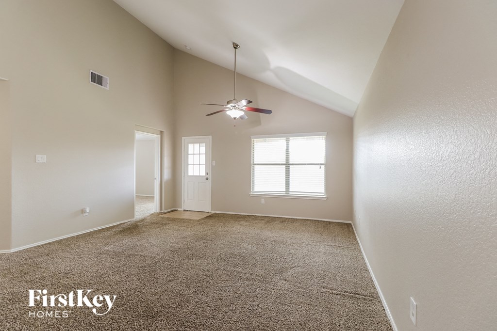 a spacious living room with carpet and a ceiling fan