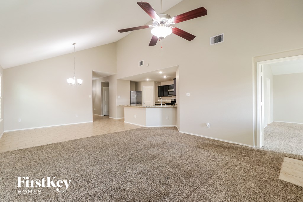 a spacious living room with carpet and a ceiling fan