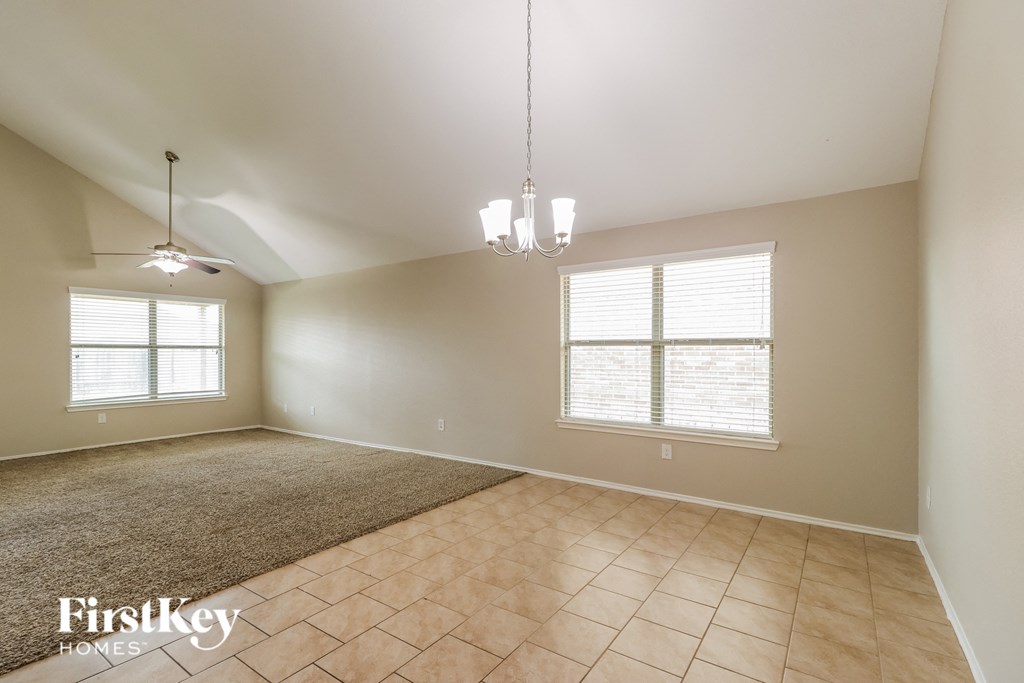 a spacious living room with tiled floors and a ceiling fan