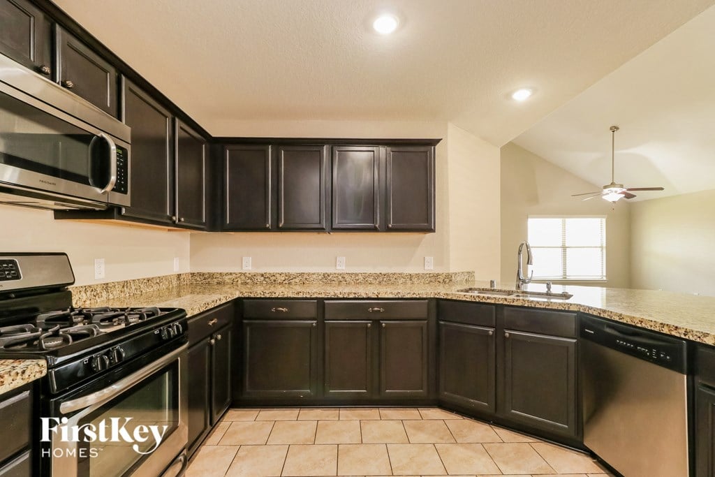 a kitchen with black cabinets and granite counter tops and a stove and microwave