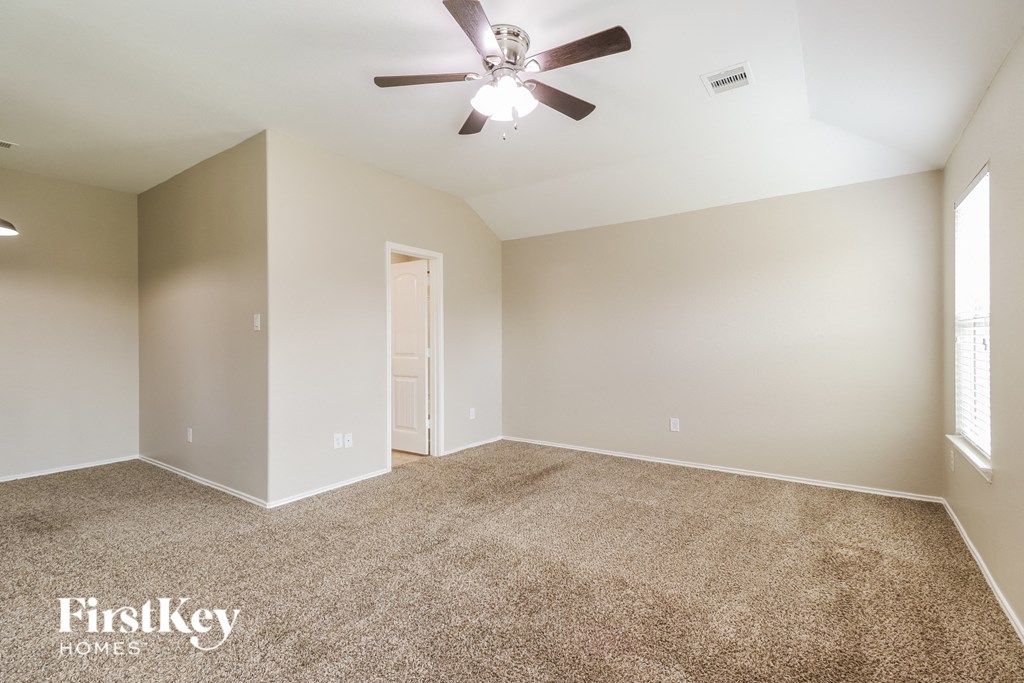 a spacious living room with carpet and a ceiling fan