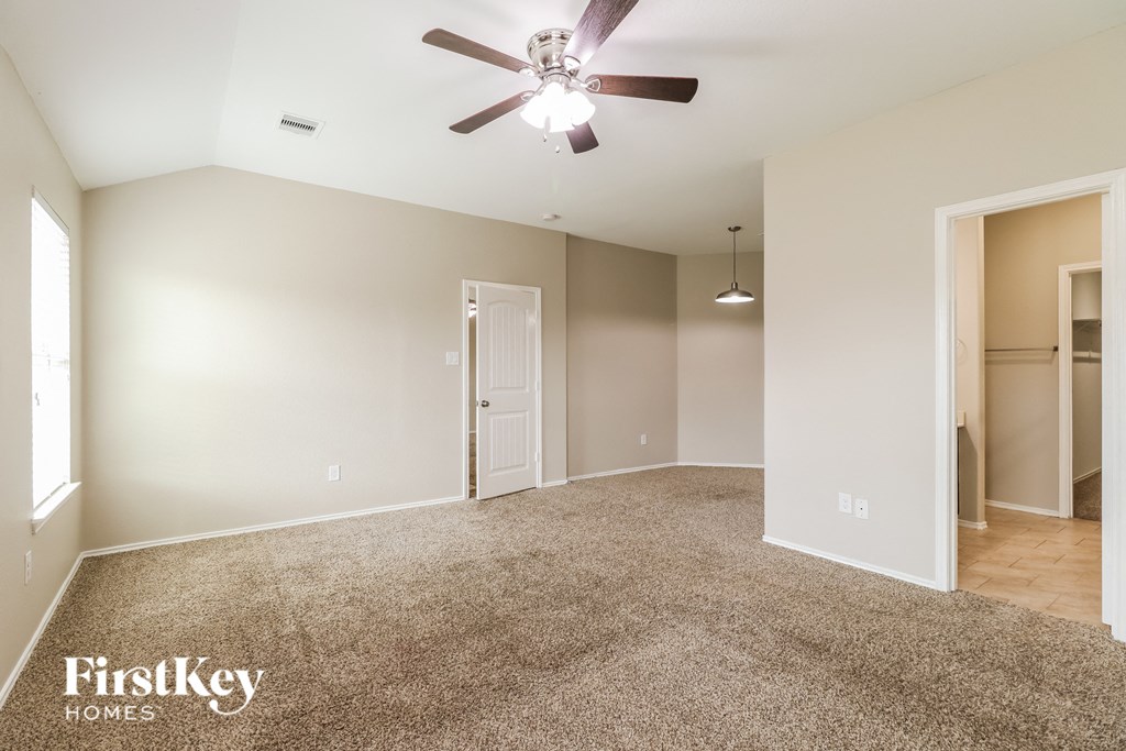 a spacious living room with carpet and a ceiling fan