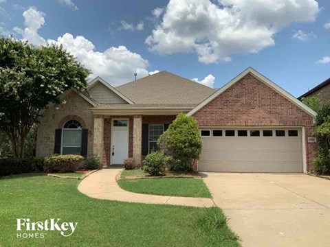 the front of a brick house with a garage and a lawn