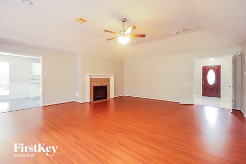 A spacious room with a fireplace and wooden flooring.