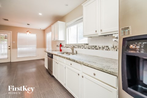 A kitchen with white cabinets and a granite countertop.