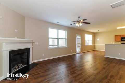 an empty living room with a fireplace and a ceiling fan