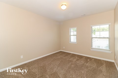 the second bedroom is spacious and clean with carpet and two windows