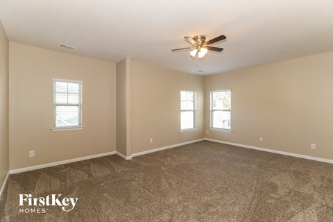 the master bedroom has a carpeted floor and a ceiling fan