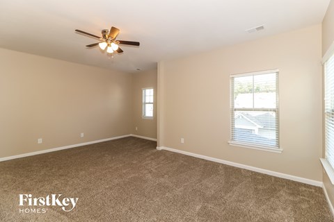 an empty living room with carpet and a ceiling fan