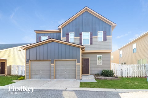 a blue and yellow house with two garages and a white fence