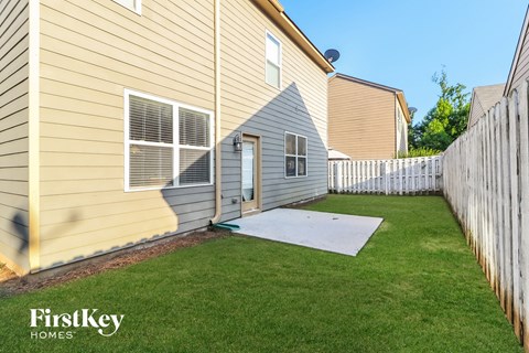 the backyard of a house with a patio and a white fence