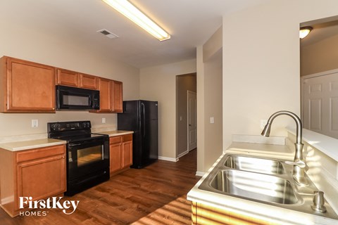 a kitchen with black appliances and wood flooring in an apartment