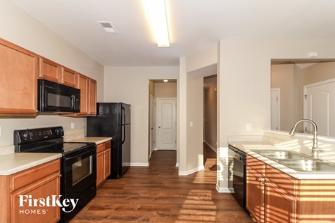 a kitchen with wooden cabinets and black appliances and a wooden floor