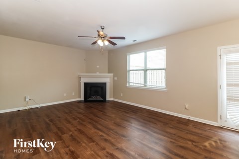 the living room of an empty house with a ceiling fan and a fireplace