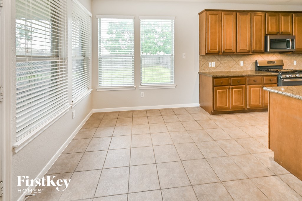 a kitchen with wood cabinets and tiled flooring and a window