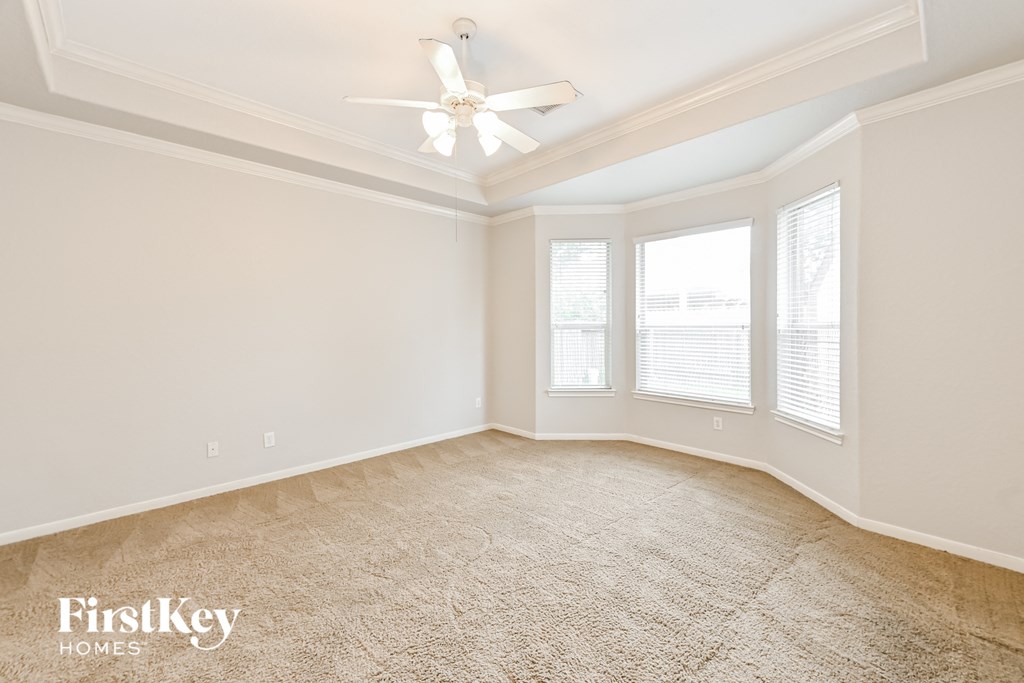 an empty living room with a ceiling fan and windows
