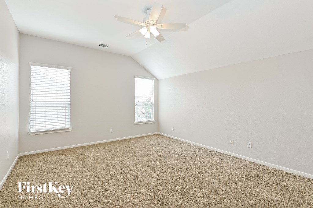 a spacious living room with carpet and a ceiling fan