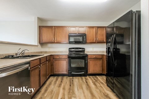 A kitchen with wooden cabinets and a black fridge.