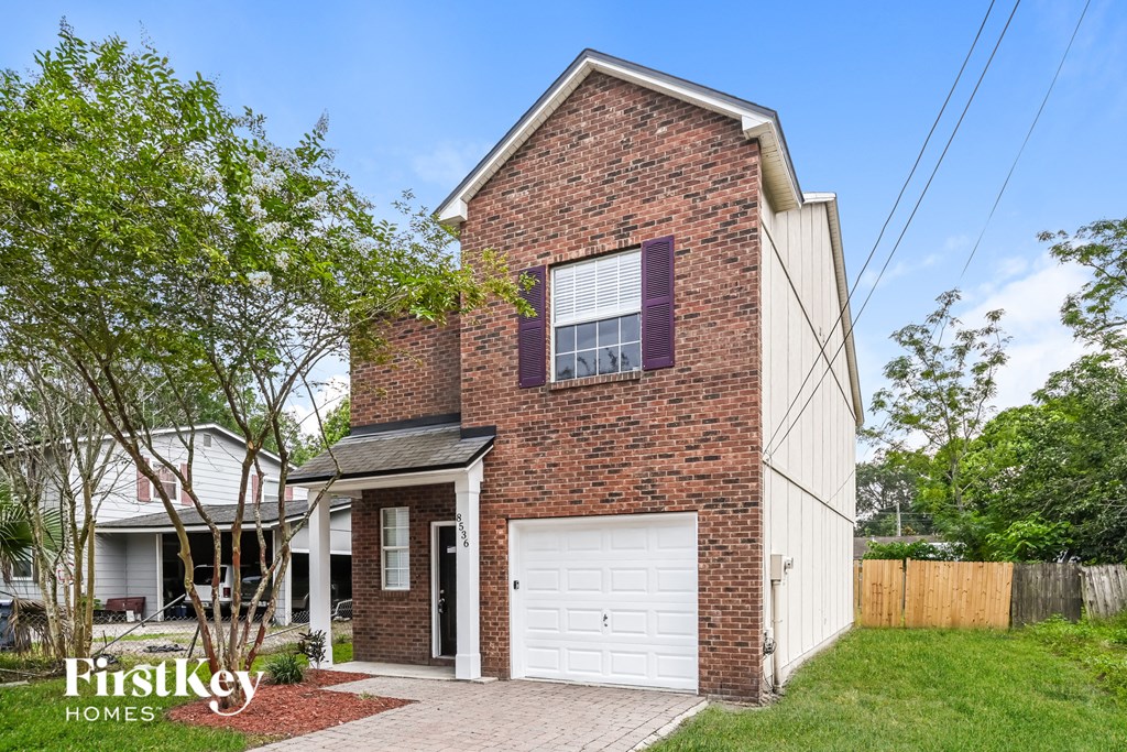 the front of a brick house with a white garage door