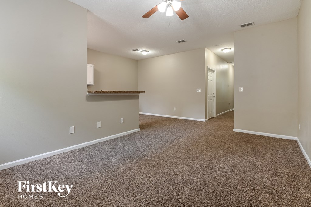 a spacious living room with carpeting and a ceiling fan