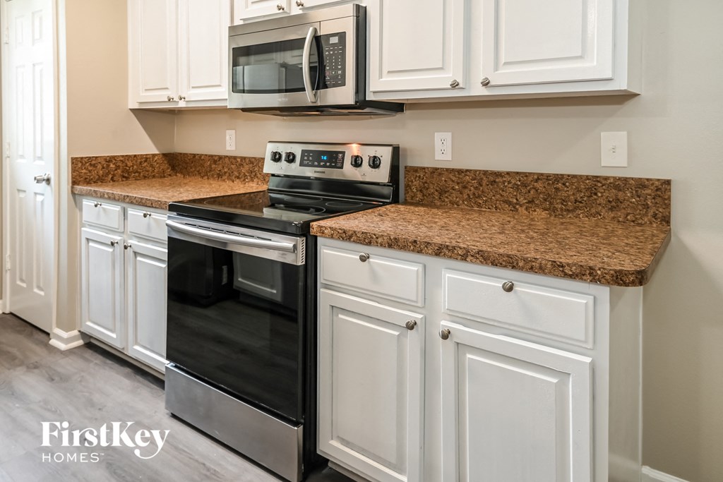 a kitchen with white cabinets and granite counter tops and black appliances
