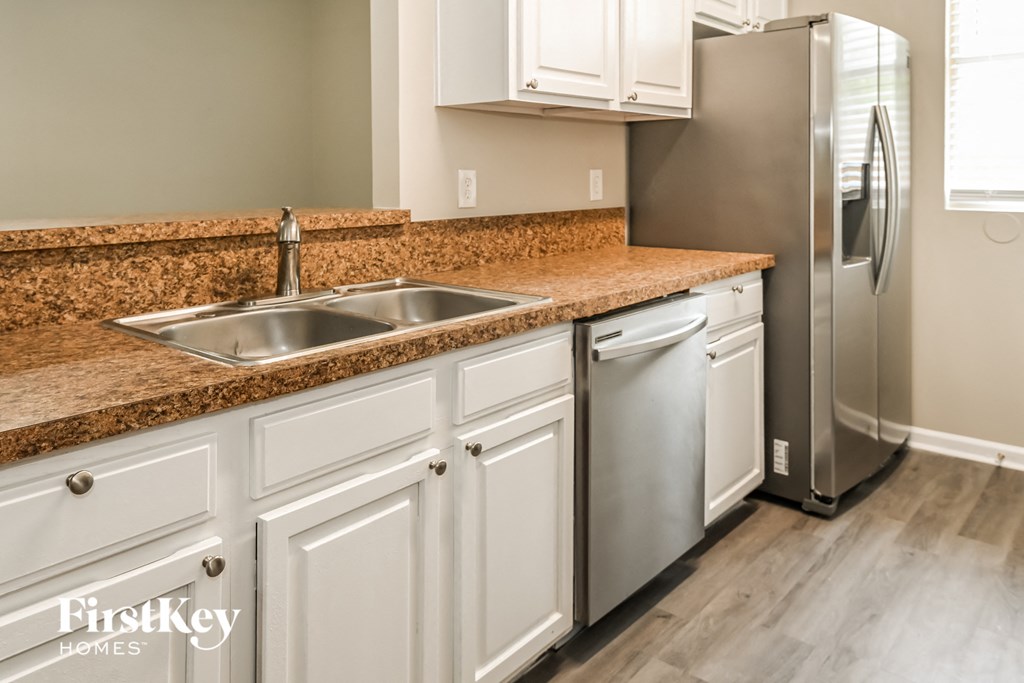 a kitchen with white cabinets and granite counter tops and a stainless steel refrigerator