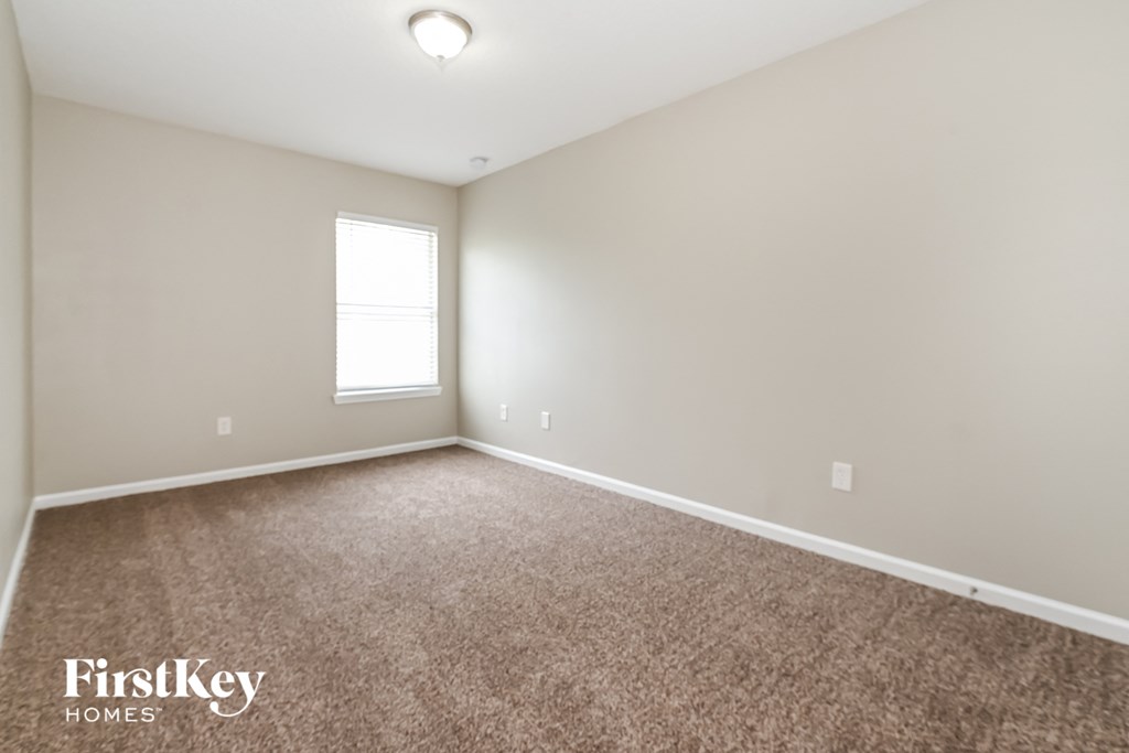 the upstairs bedroom with carpeting and a window