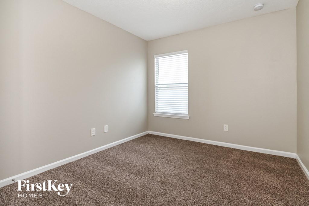 a bedroom with a carpeted floor and a window