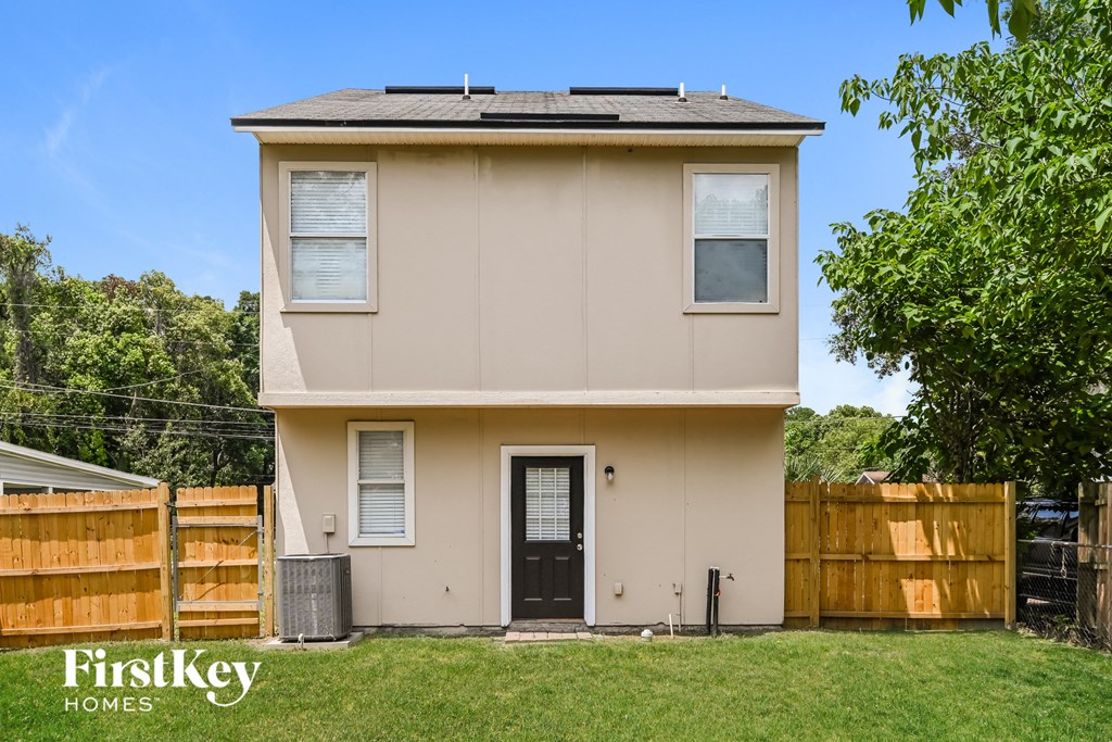 a small tan house with a yard and a wooden fence