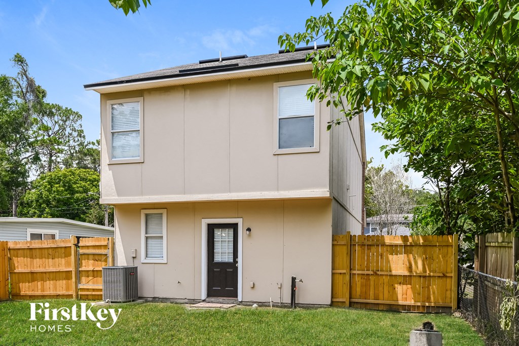 a beige house with a yard and a wooden fence