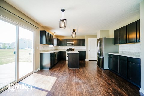 A kitchen with black cabinets and a wooden floor.