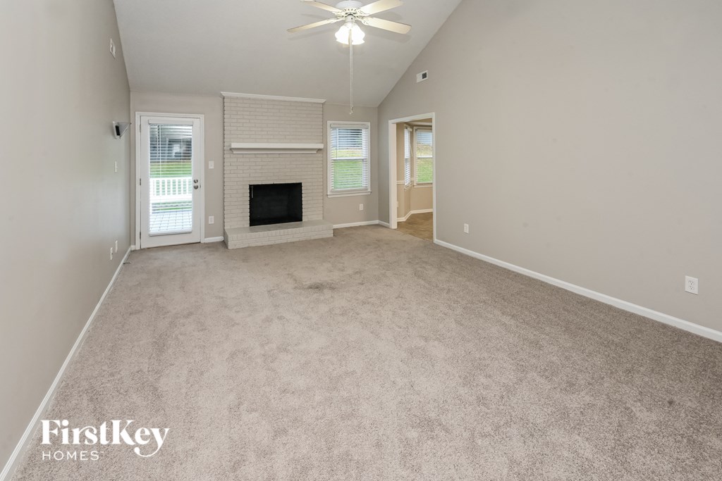 a spacious living room with a fireplace and carpeted flooring