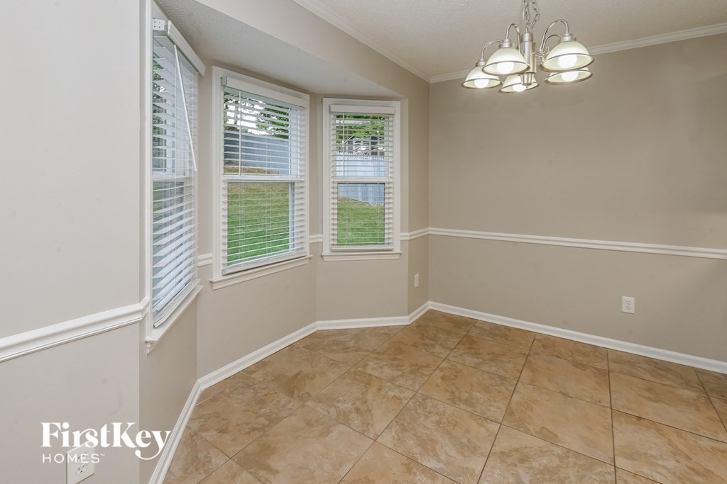 an empty dining room with three windows and a tiled floor