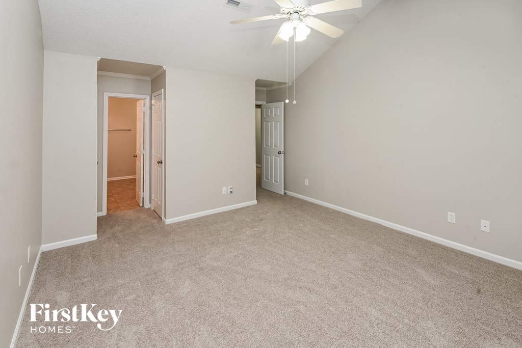 a spacious living room with carpeting and a ceiling fan