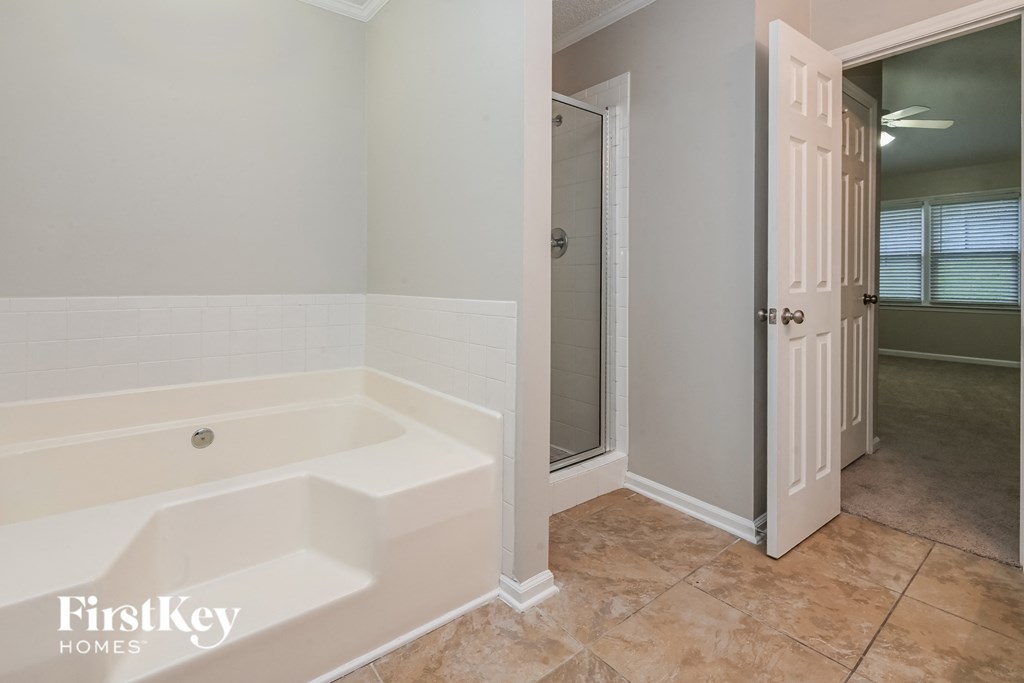 a bathroom with a large tub and a door to a shower