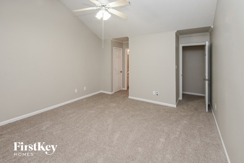 a spacious living room with carpet and a ceiling fan