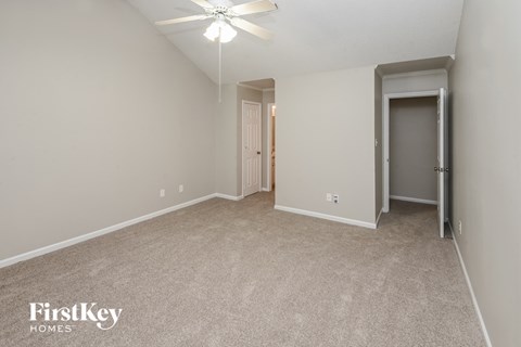 a spacious living room with carpet and a ceiling fan