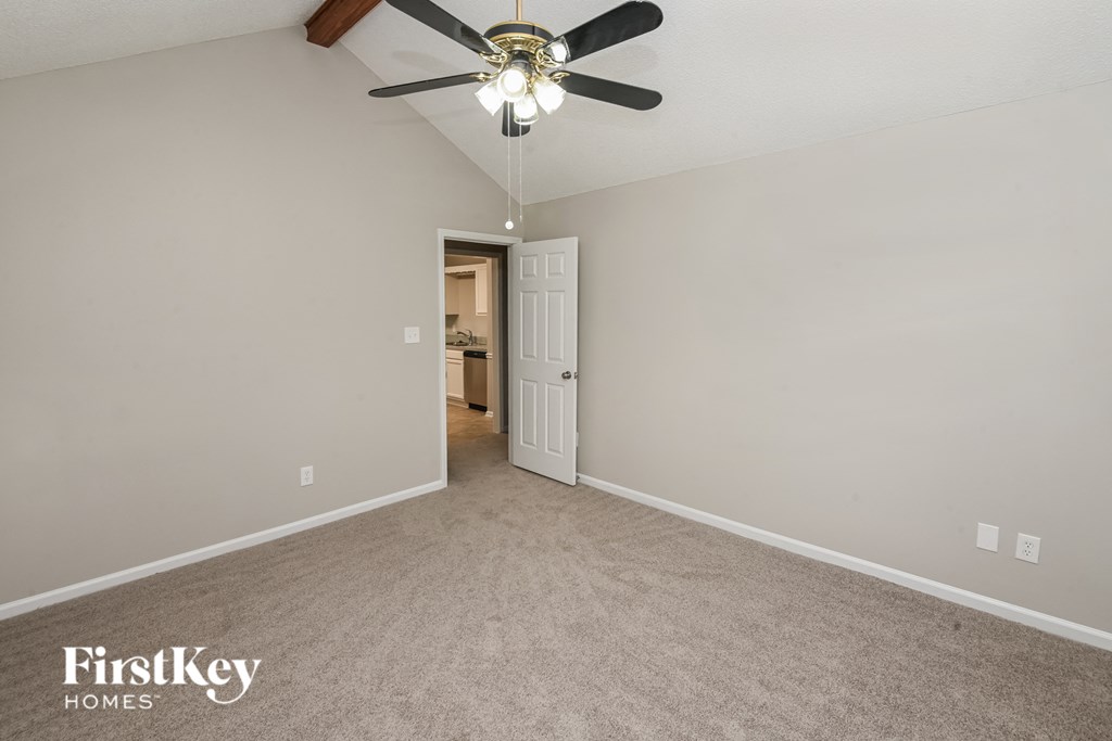 the spacious living room with ceiling fan and carpeting