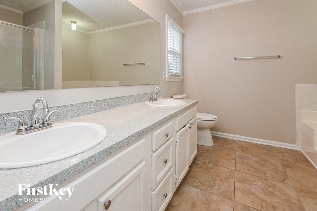 a bathroom with two sinks and a toilet and a large mirror