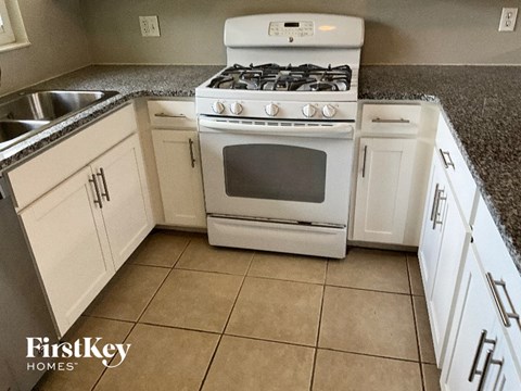 A kitchen with a white stove and cabinets.