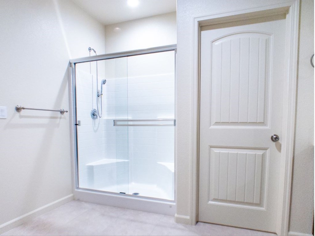 a bathroom with a shower and a white door