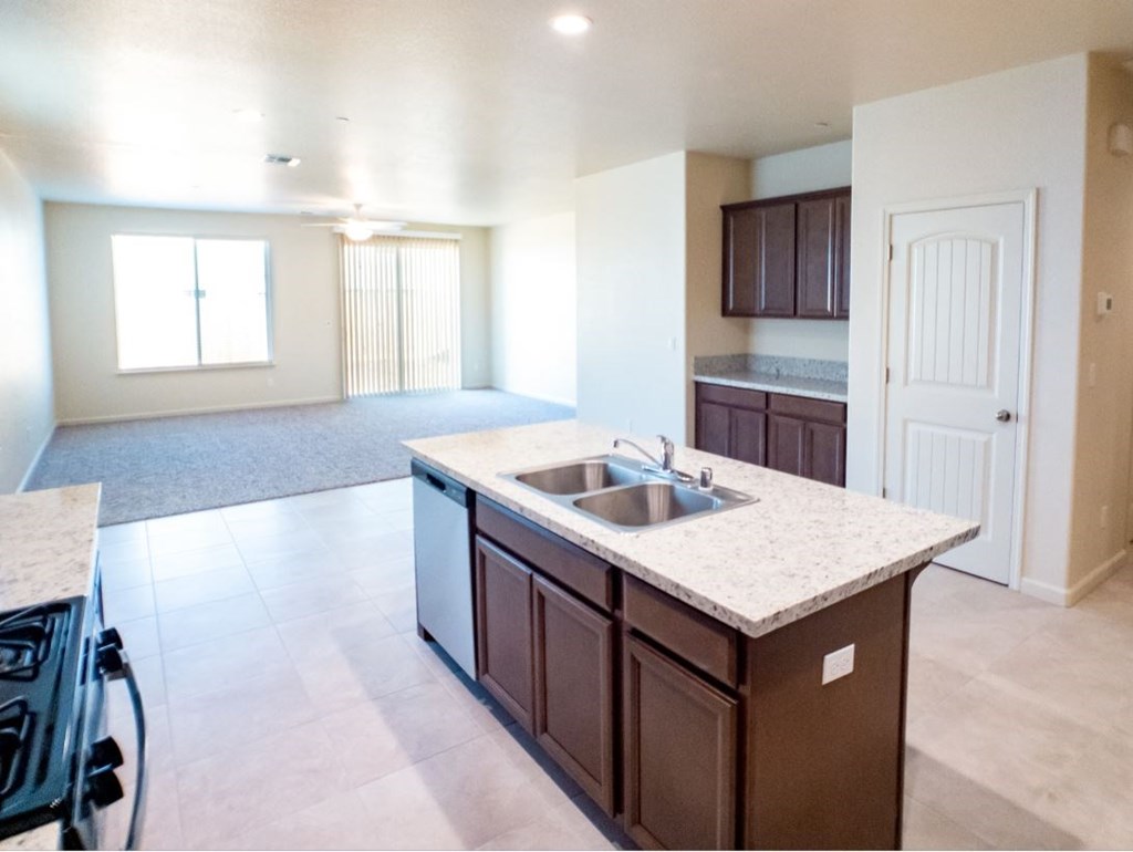 an empty kitchen with a sink and an empty living room