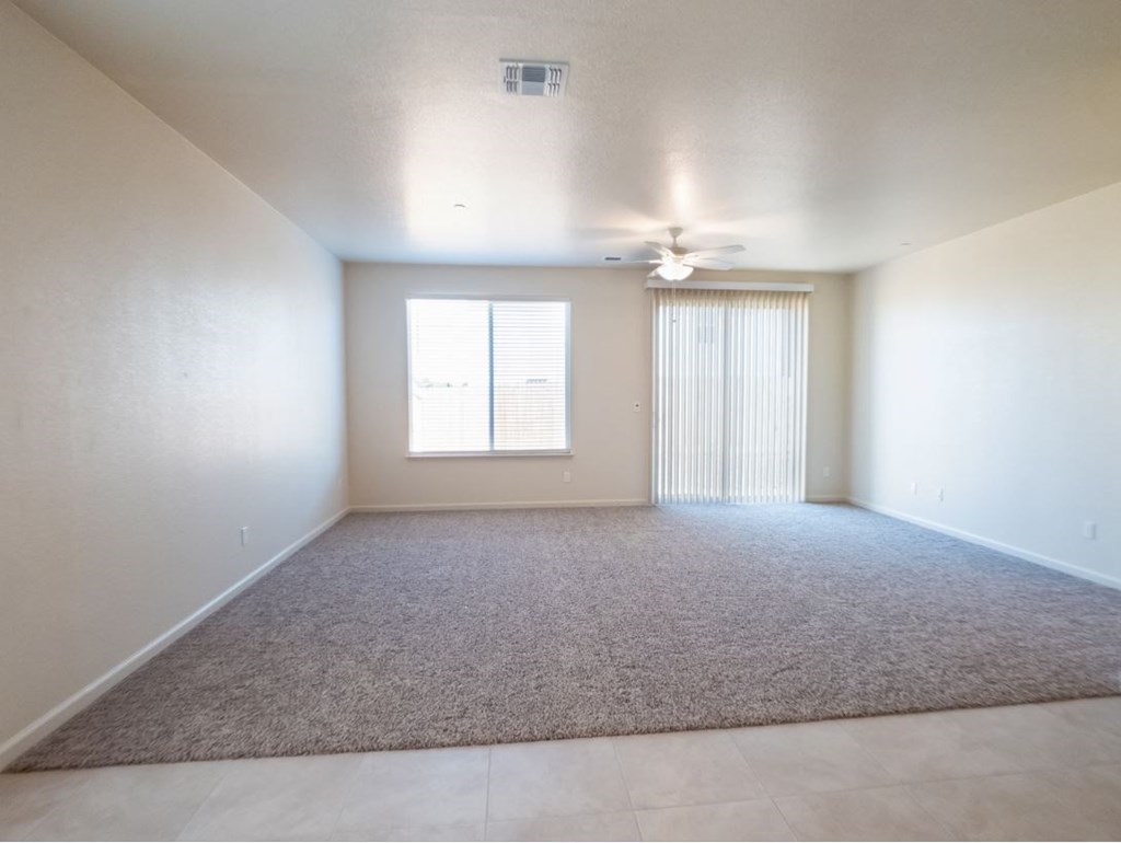 an empty living room with a ceiling fan and a window