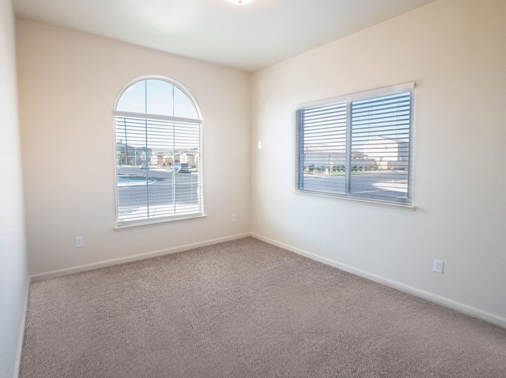 an empty living room with a window and carpet