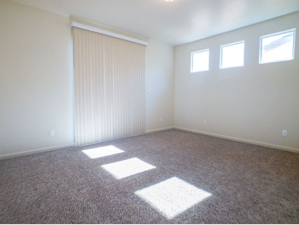 an empty living room with carpet and a window
