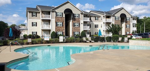 A large apartment complex with a pool in front.