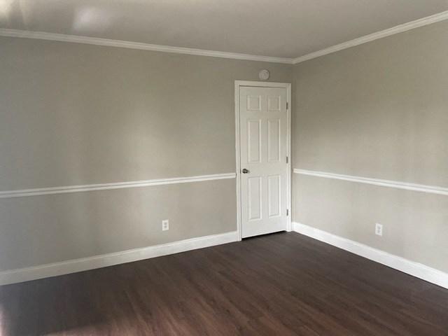 an empty living room with a white door and wood floors