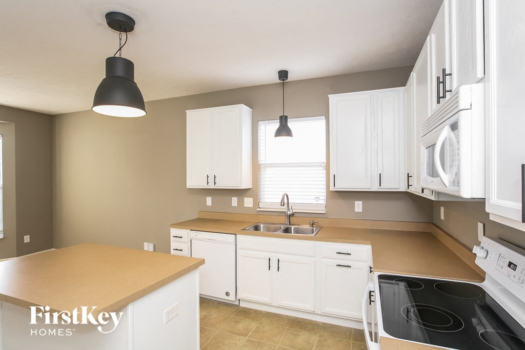 a kitchen with white cabinets and appliances and a sink
